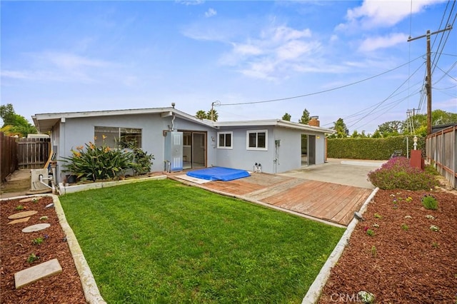 rear view of property featuring a lawn, a fenced backyard, and stucco siding