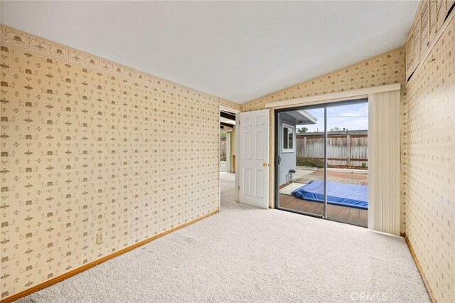 spare room with vaulted ceiling, carpet floors, and wallpapered walls