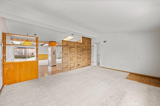 unfurnished living room featuring vaulted ceiling with beams and light colored carpet