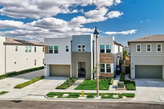 contemporary home featuring driveway, an attached garage, a residential view, and stucco siding