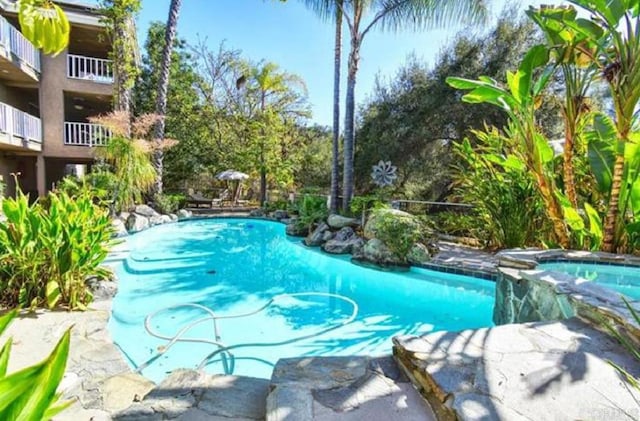 view of pool with a pool with connected hot tub