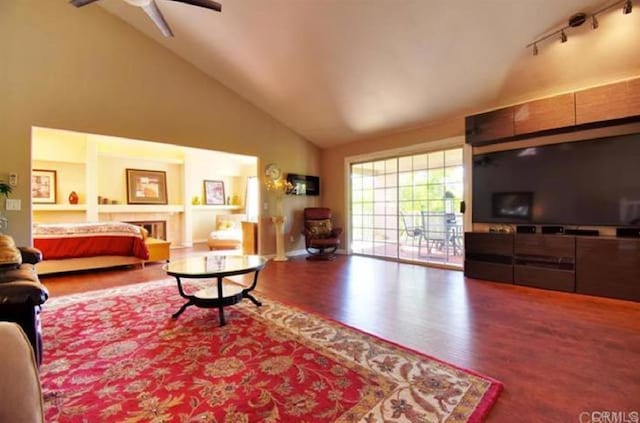 living room with rail lighting, a fireplace, high vaulted ceiling, and wood finished floors