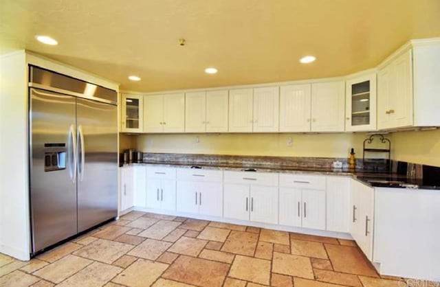 kitchen featuring dark countertops, stainless steel built in refrigerator, stone tile floors, and recessed lighting