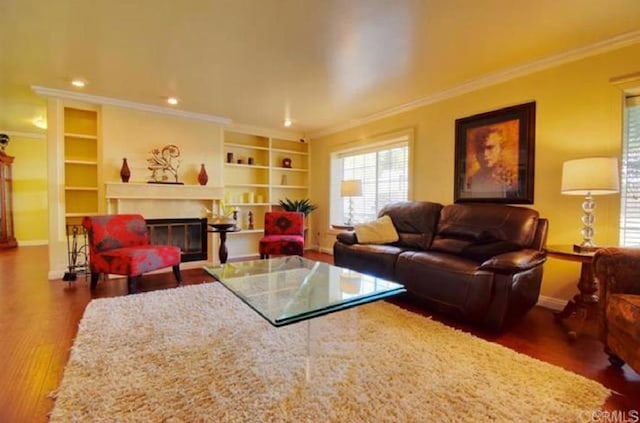 living room with ornamental molding, a glass covered fireplace, baseboards, and wood finished floors