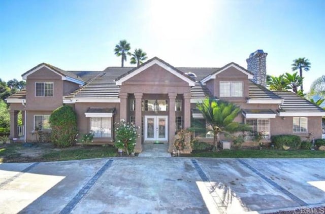 view of front of home with french doors, a chimney, and stucco siding