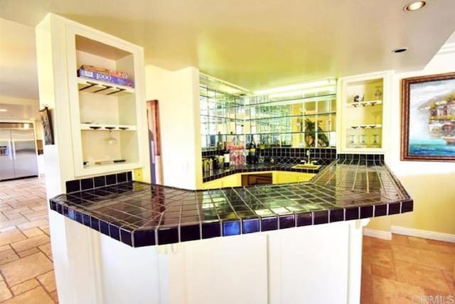 bar with stone tile floors, stainless steel built in fridge, built in shelves, backsplash, and recessed lighting