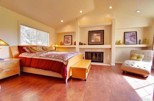 bedroom with high vaulted ceiling, recessed lighting, a fireplace, and wood finished floors