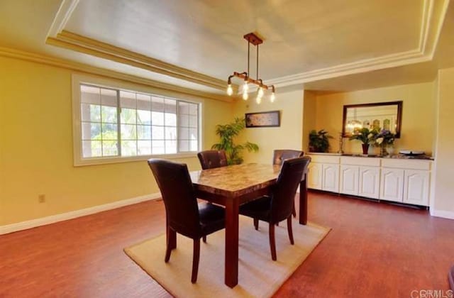 dining area with baseboards, a tray ceiling, dark wood-style flooring, and ornamental molding