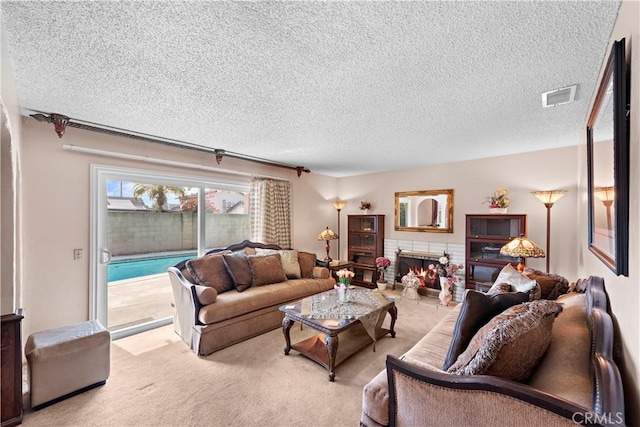 living area with a brick fireplace, visible vents, a textured ceiling, and light colored carpet