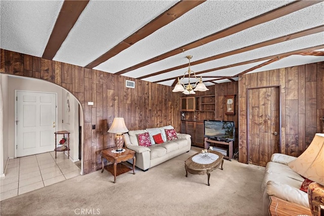 tiled living area featuring wood walls, beamed ceiling, carpet, and visible vents