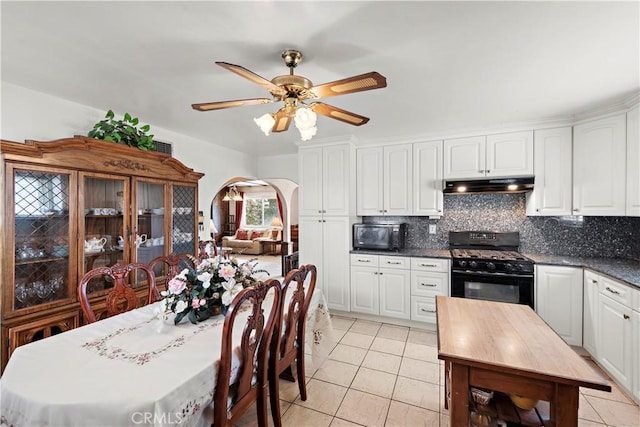 kitchen with arched walkways, under cabinet range hood, white cabinets, black appliances, and tasteful backsplash