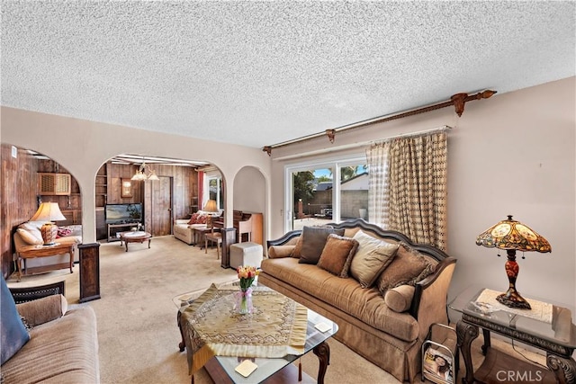 carpeted living area with arched walkways and a textured ceiling