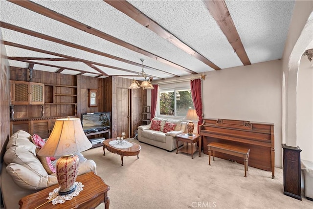 living room with a textured ceiling, carpet floors, beam ceiling, and wooden walls