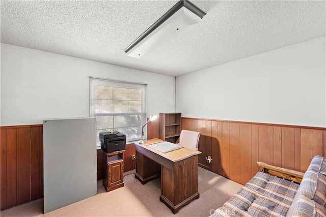 carpeted office space featuring a textured ceiling, wood walls, and wainscoting