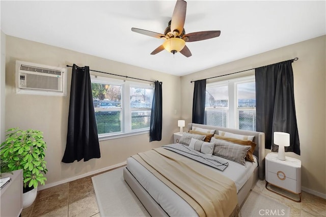 bedroom featuring an AC wall unit, a ceiling fan, and baseboards