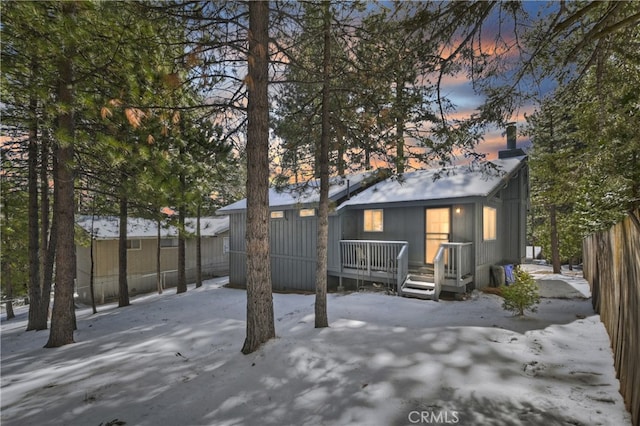 snow covered property with fence and a deck