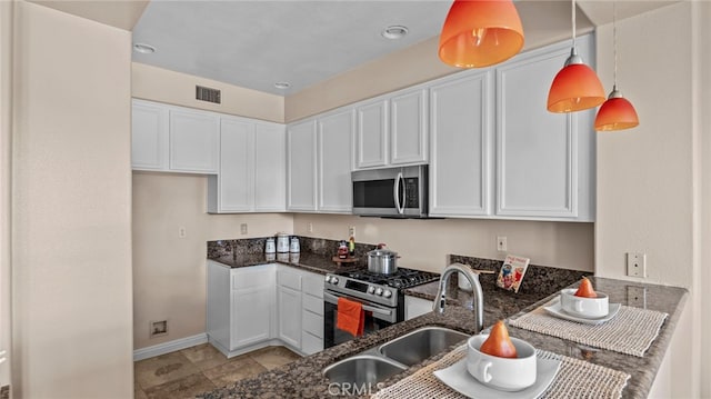 kitchen featuring appliances with stainless steel finishes, white cabinets, and dark stone countertops