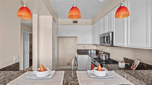 kitchen with white cabinetry, visible vents, stainless steel appliances, and dark stone countertops