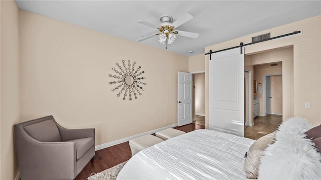 bedroom featuring a barn door, baseboards, ceiling fan, and wood finished floors