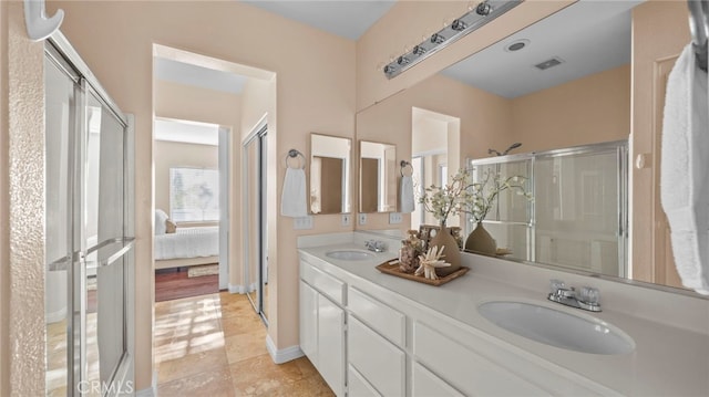 ensuite bathroom with connected bathroom, visible vents, a sink, and a shower stall