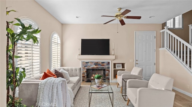 tiled living area featuring plenty of natural light, a lit fireplace, baseboards, and ceiling fan