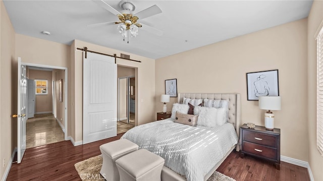 bedroom with dark wood-style floors, a barn door, baseboards, and ceiling fan