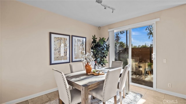 dining space featuring track lighting, light tile patterned flooring, and baseboards