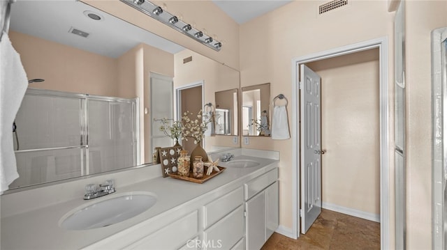 bathroom featuring double vanity, an enclosed shower, a sink, and visible vents