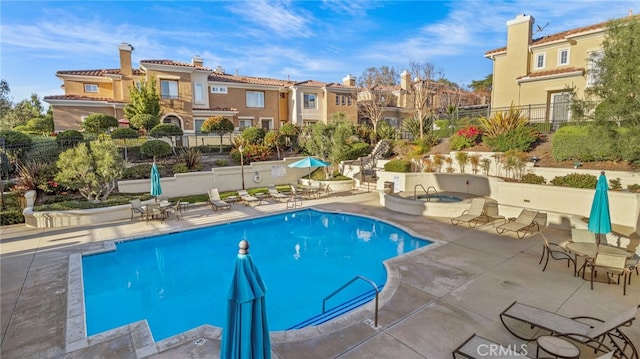 community pool featuring a residential view, a patio, and fence