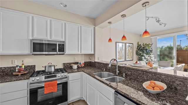 kitchen with white cabinetry, dark stone countertops, appliances with stainless steel finishes, and a sink