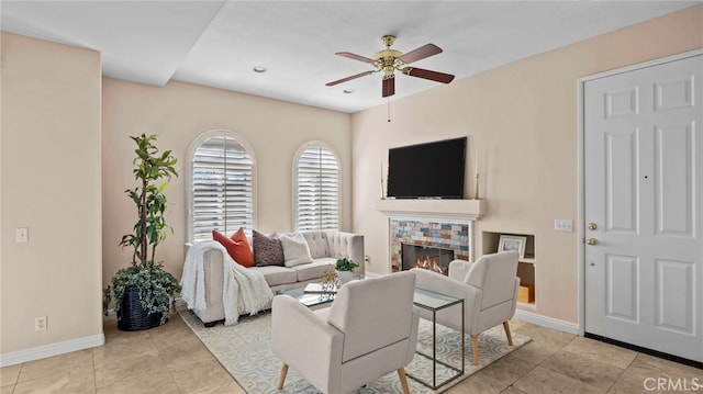 tiled living area featuring a ceiling fan, baseboards, and a tiled fireplace