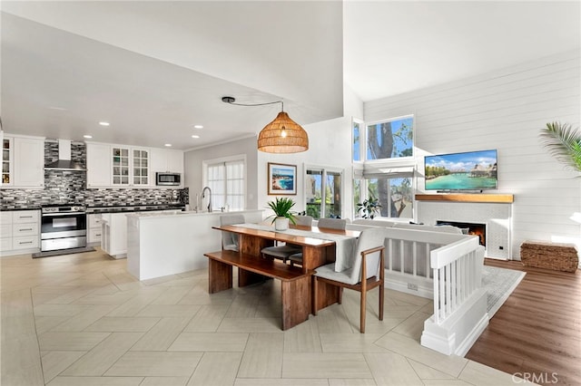 dining area with a towering ceiling, a warm lit fireplace, plenty of natural light, and recessed lighting