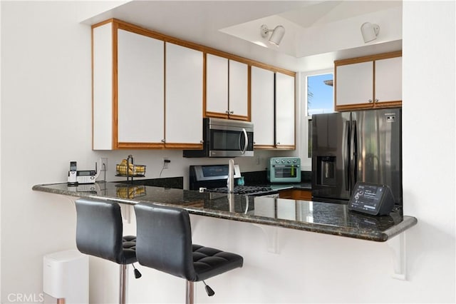 kitchen with a peninsula, appliances with stainless steel finishes, and white cabinets