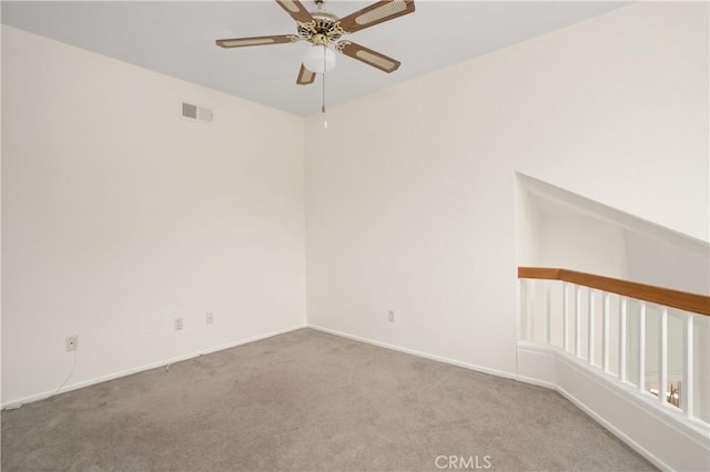 carpeted empty room with baseboards, visible vents, and a ceiling fan