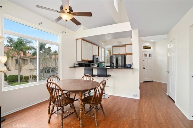 dining space with a ceiling fan, baseboards, and wood finished floors