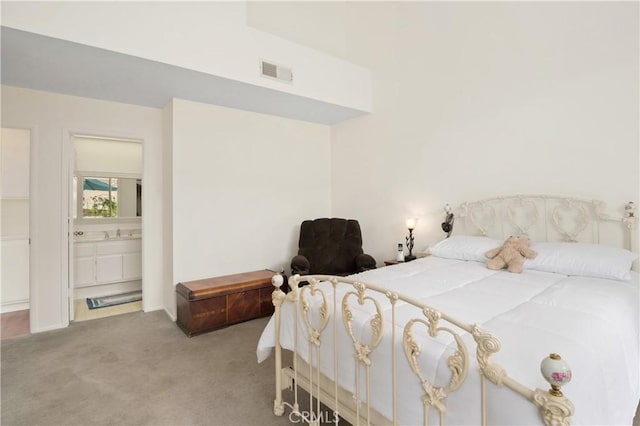 carpeted bedroom featuring ensuite bath and visible vents