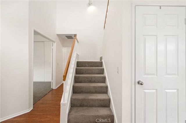 staircase featuring baseboards, visible vents, and wood finished floors