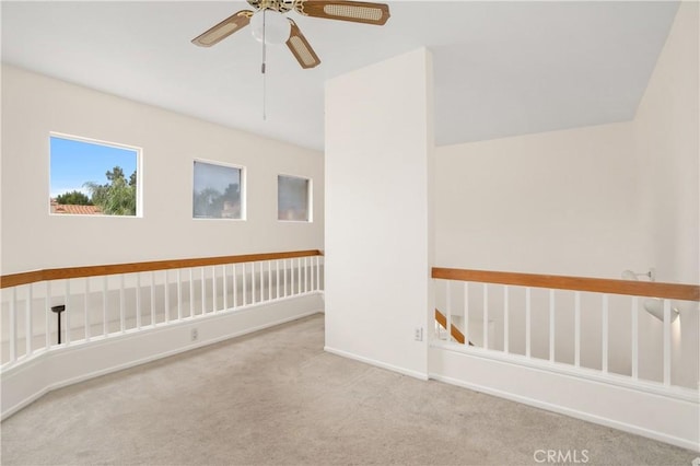 carpeted empty room featuring baseboards and a ceiling fan