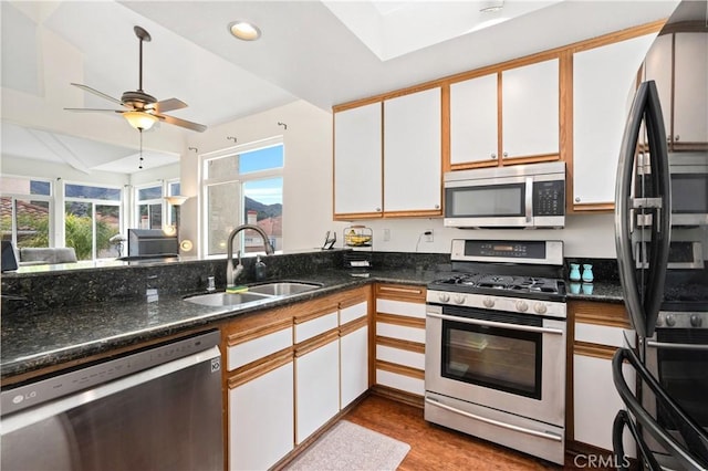 kitchen with wood finished floors, appliances with stainless steel finishes, a sink, and white cabinets