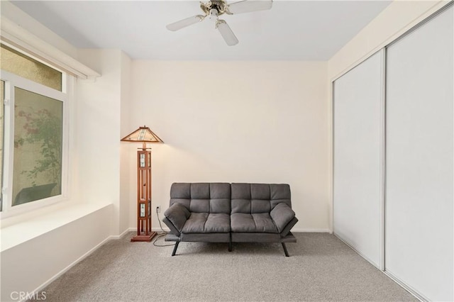 living area featuring carpet, baseboards, and ceiling fan