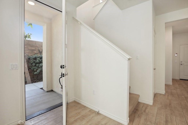 entryway with light wood-style flooring, stairway, and baseboards