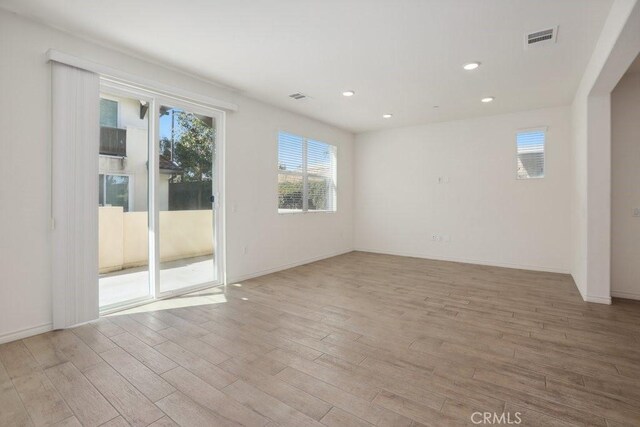 empty room with light wood-style flooring, visible vents, and recessed lighting