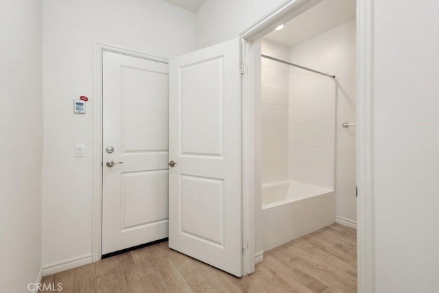 full bath featuring tub / shower combination, wood finished floors, and baseboards