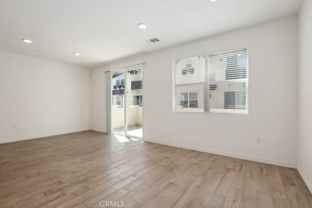 empty room with light wood-style floors, recessed lighting, visible vents, and baseboards