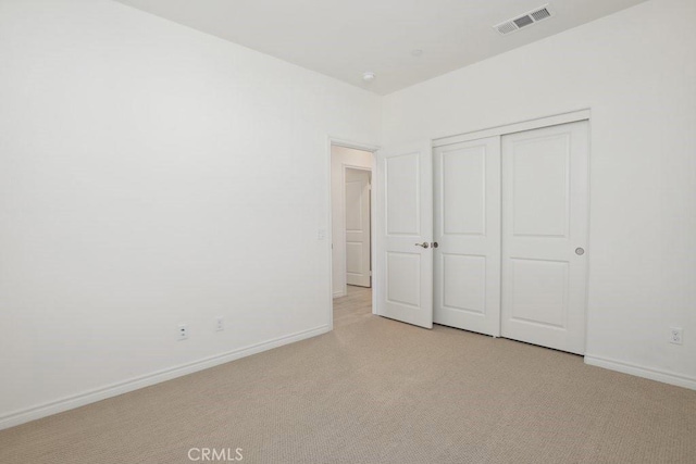 unfurnished bedroom featuring light carpet, baseboards, visible vents, and a closet