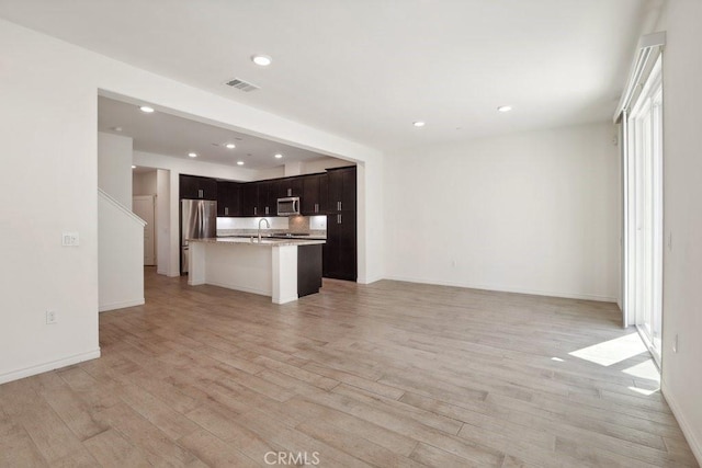 unfurnished living room featuring visible vents, a sink, light wood-style flooring, and recessed lighting