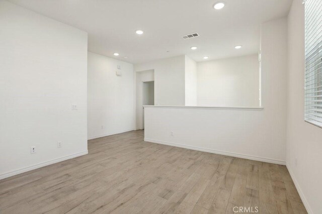 spare room featuring light wood-type flooring, baseboards, visible vents, and recessed lighting