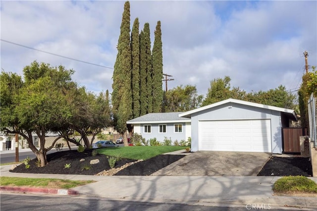 ranch-style home featuring a front yard, concrete driveway, and an attached garage