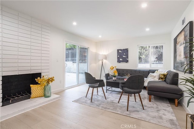 living room with visible vents, baseboards, wood finished floors, a fireplace, and recessed lighting