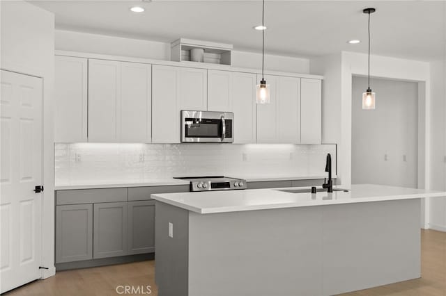 kitchen with light wood-style flooring, gray cabinets, appliances with stainless steel finishes, and a sink